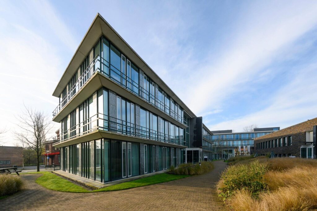 Modern kantoorgebouw aan de De Cuserstraat met glazen gevels en omringende tuinpaden.